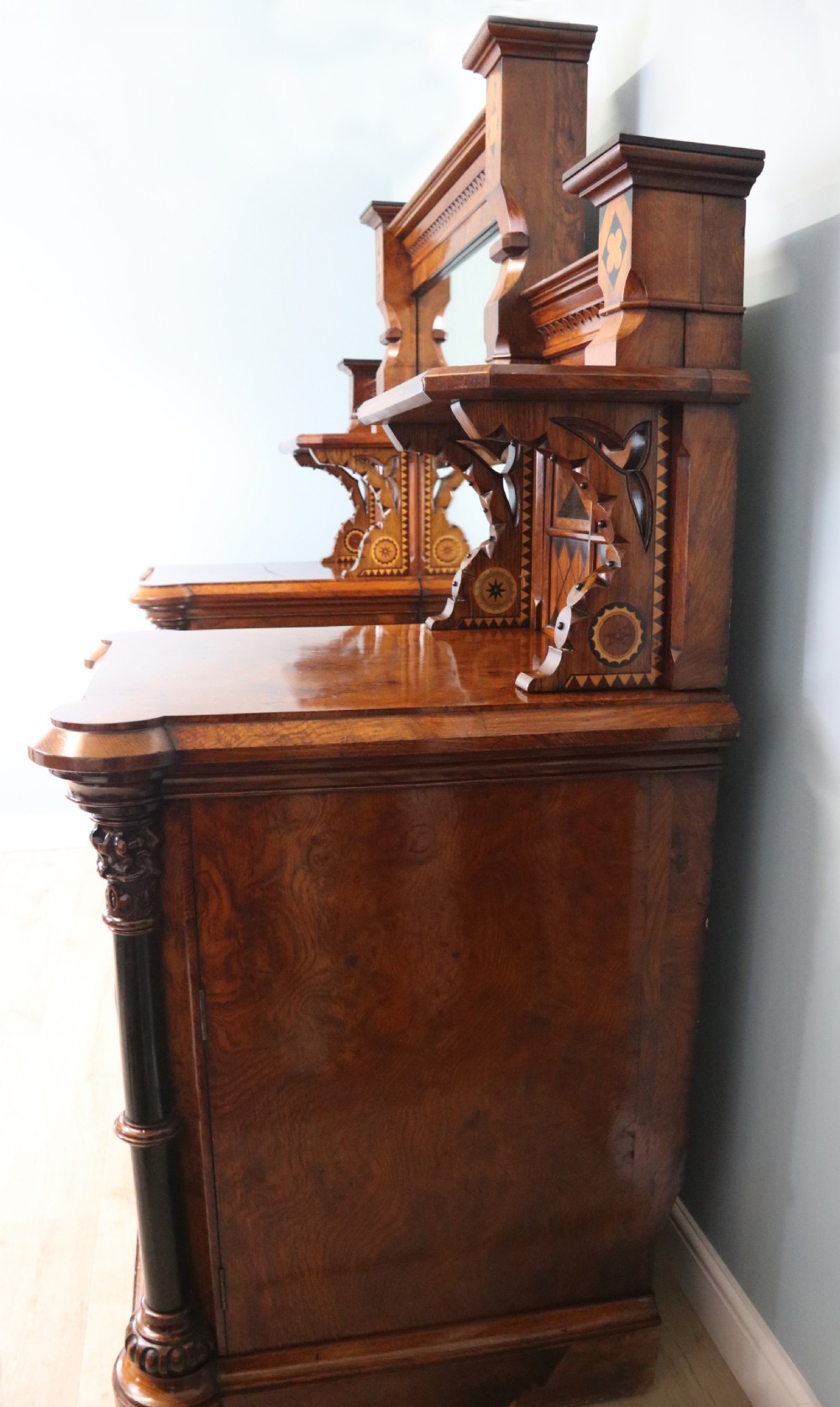 A Victorian Gothic Revival sideboard crafted from pollard oak featuring intricate geometric wood inlays, turned black columns, twin pedestal cupboards, and a tiered upper superstructure. View II