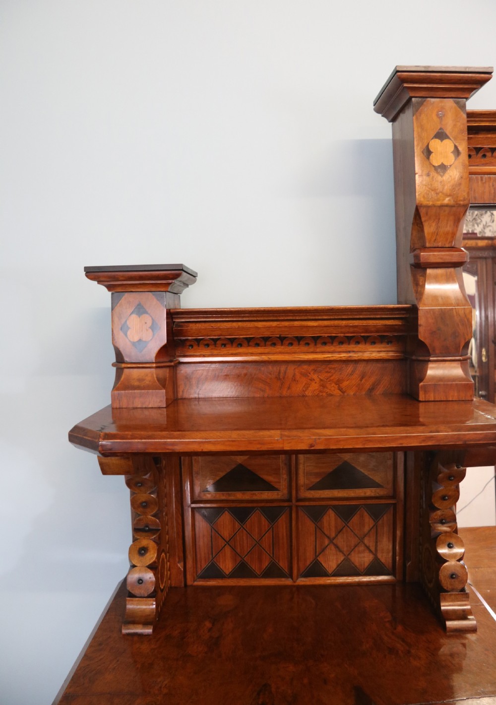 A Victorian Gothic Revival sideboard crafted from pollard oak featuring intricate geometric wood inlays, turned black columns, twin pedestal cupboards, and a tiered upper superstructure. View XI