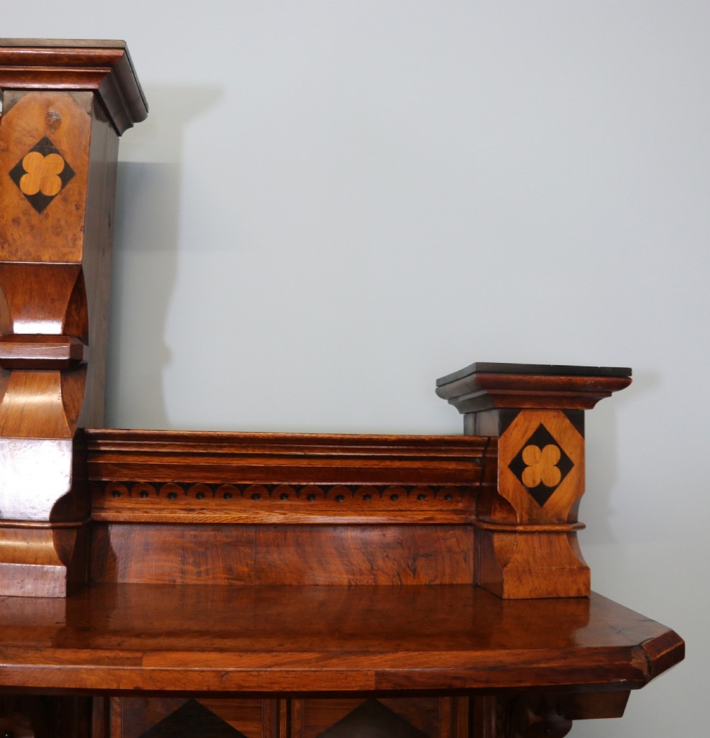 A Victorian Gothic Revival sideboard crafted from pollard oak featuring intricate geometric wood inlays, turned black columns, twin pedestal cupboards, and a tiered upper superstructure. View XII
