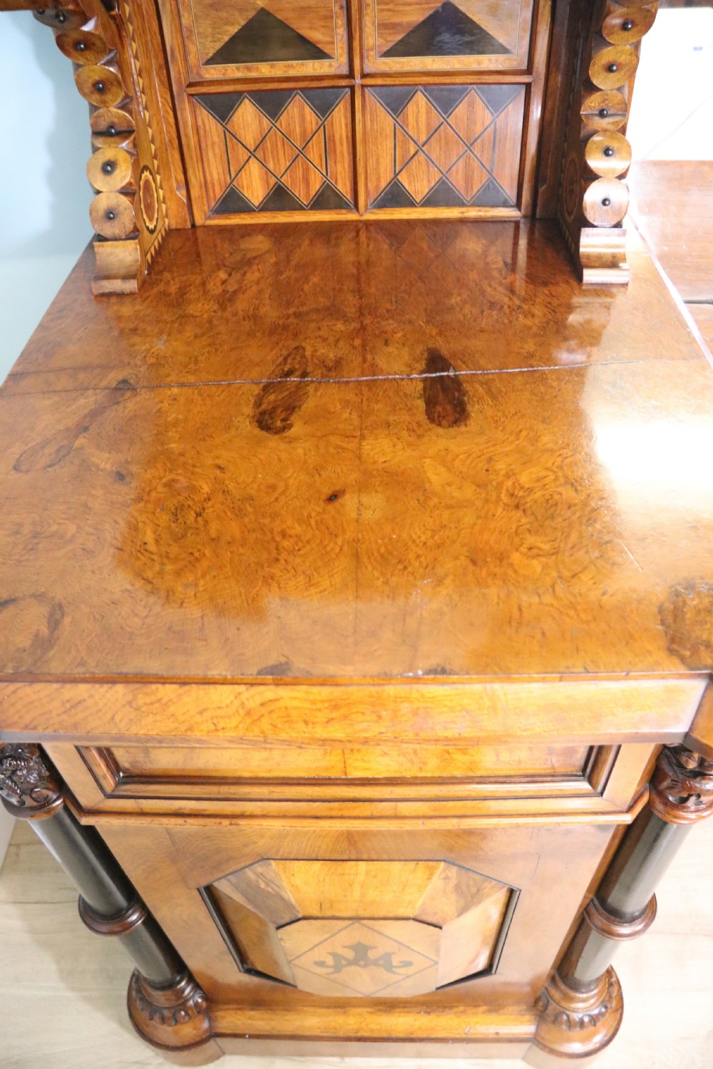 A Victorian Gothic Revival sideboard crafted from pollard oak featuring intricate geometric wood inlays, turned black columns, twin pedestal cupboards, and a tiered upper superstructure. View XIX