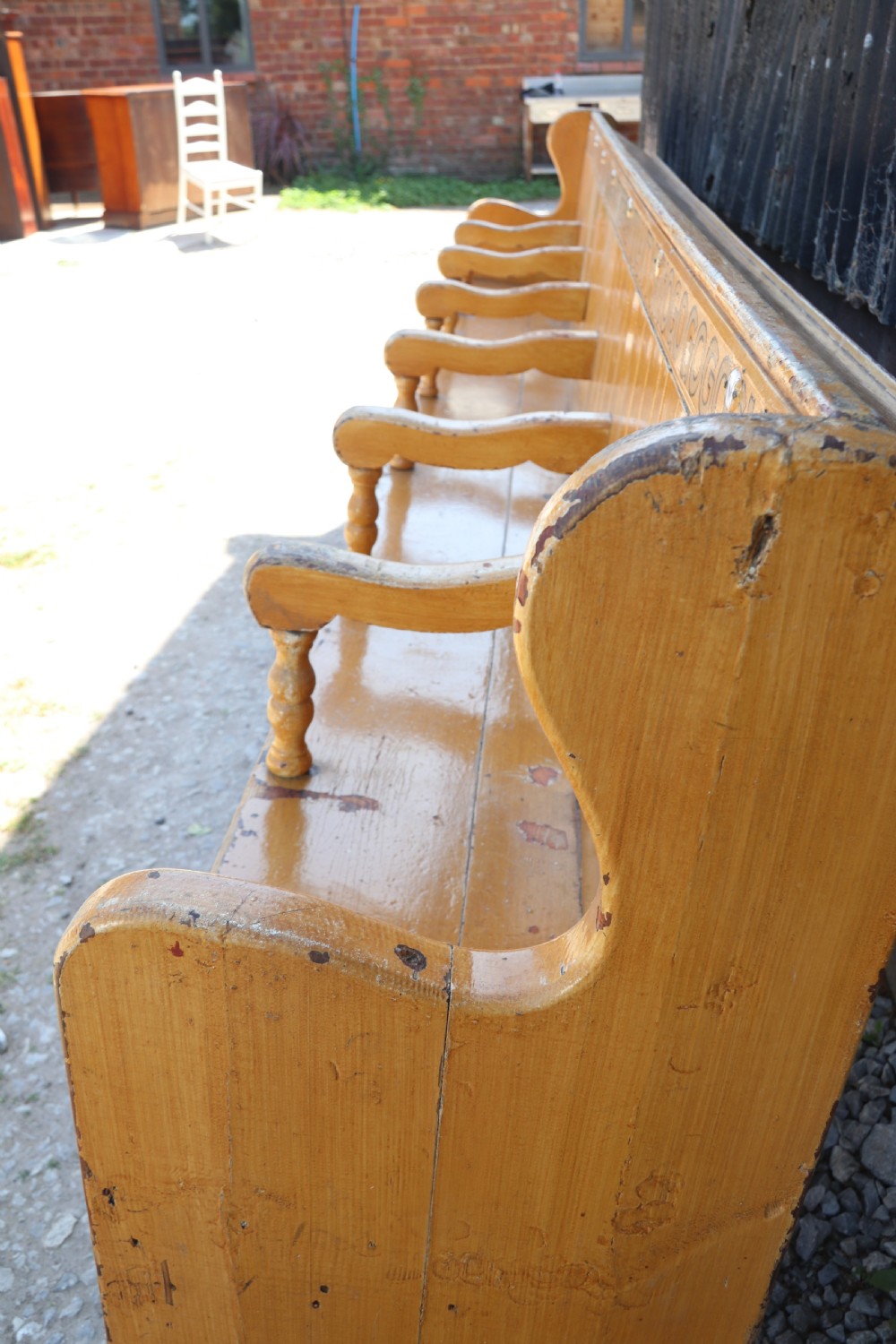 A long Victorian painted pine chapel bench featuring a vertical panelled back, turned arm dividers, and Welsh script along the top rail. View IV