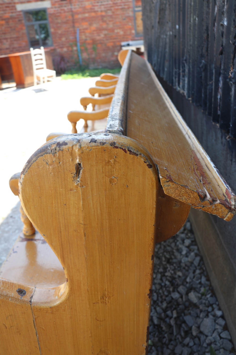 A long Victorian painted pine chapel bench featuring a vertical panelled back, turned arm dividers, and Welsh script along the top rail. View VI