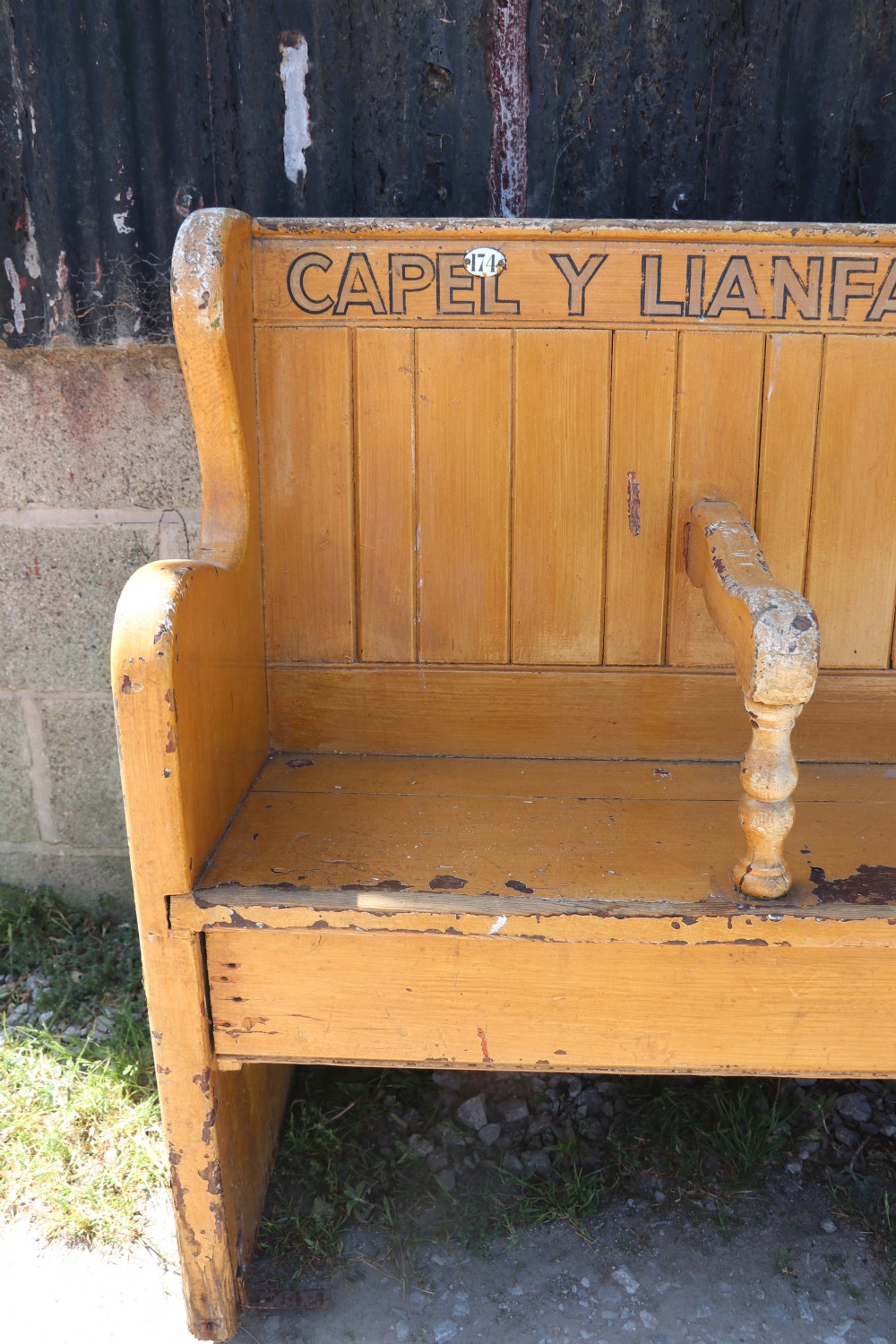 A long Victorian painted pine chapel bench featuring a vertical panelled back, turned arm dividers, and Welsh script along the top rail. View VII