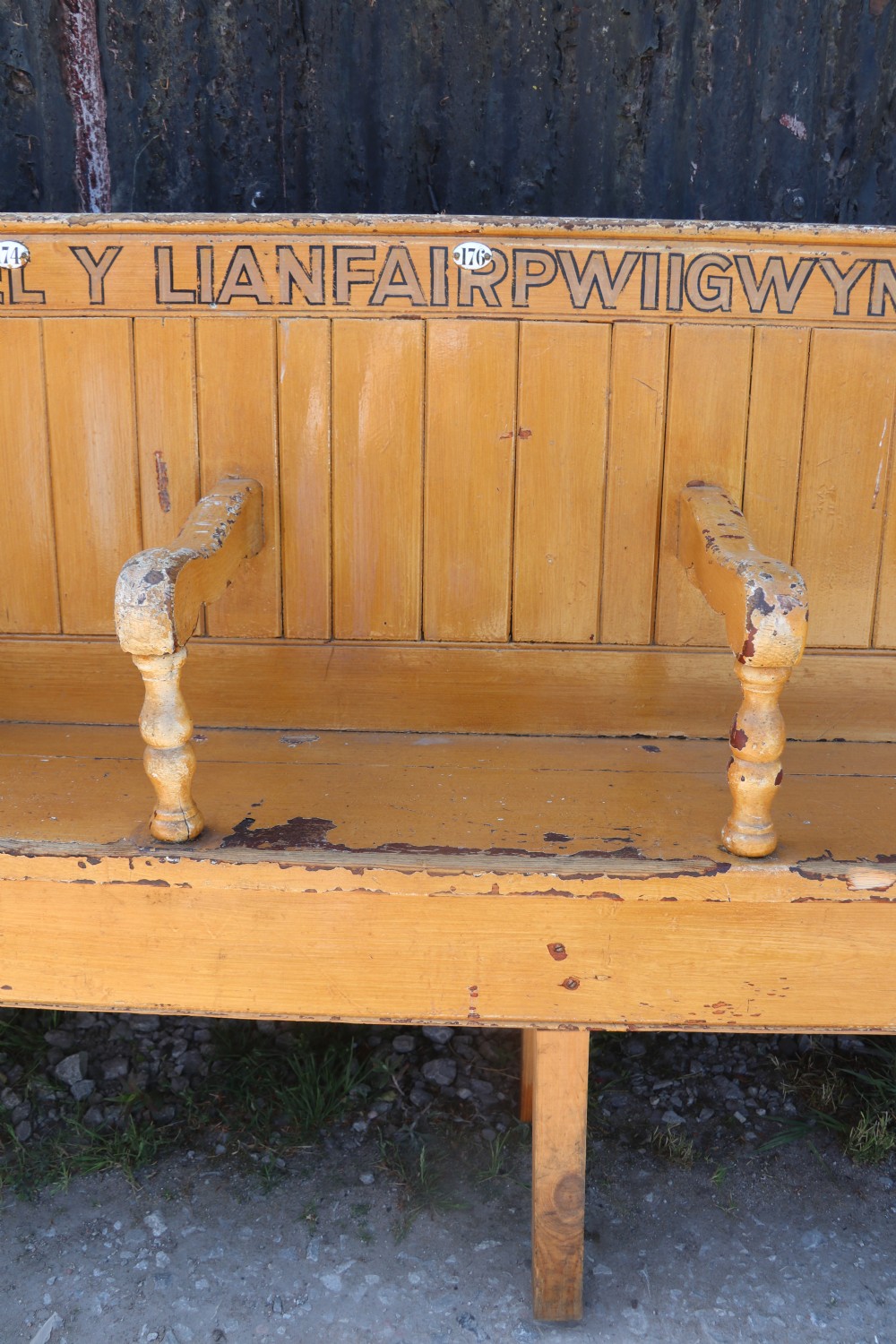 A long Victorian painted pine chapel bench featuring a vertical panelled back, turned arm dividers, and Welsh script along the top rail. View VIII