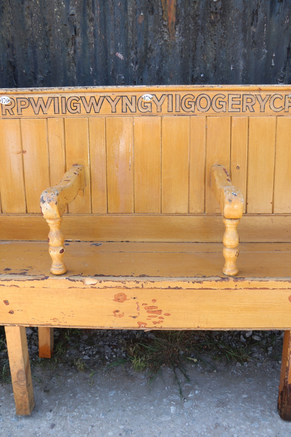 A long Victorian painted pine chapel bench featuring a vertical panelled back, turned arm dividers, and Welsh script along the top rail. View IX