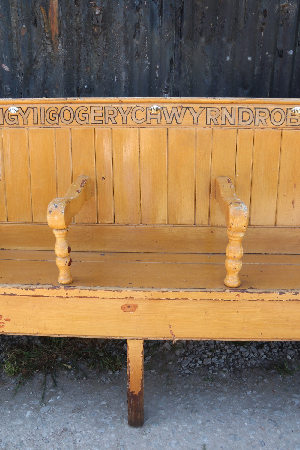 A long Victorian painted pine chapel bench featuring a vertical panelled back, turned arm dividers, and Welsh script along the top rail. View X