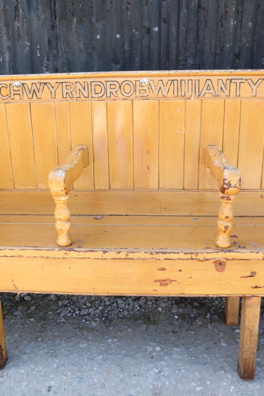 A long Victorian painted pine chapel bench featuring a vertical panelled back, turned arm dividers, and Welsh script along the top rail. View XI