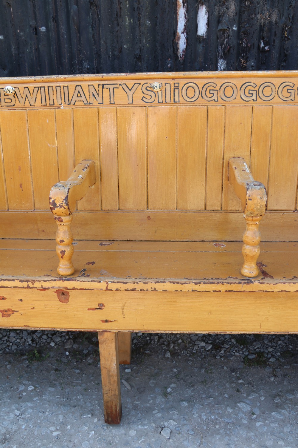 A long Victorian painted pine chapel bench featuring a vertical panelled back, turned arm dividers, and Welsh script along the top rail. View XII