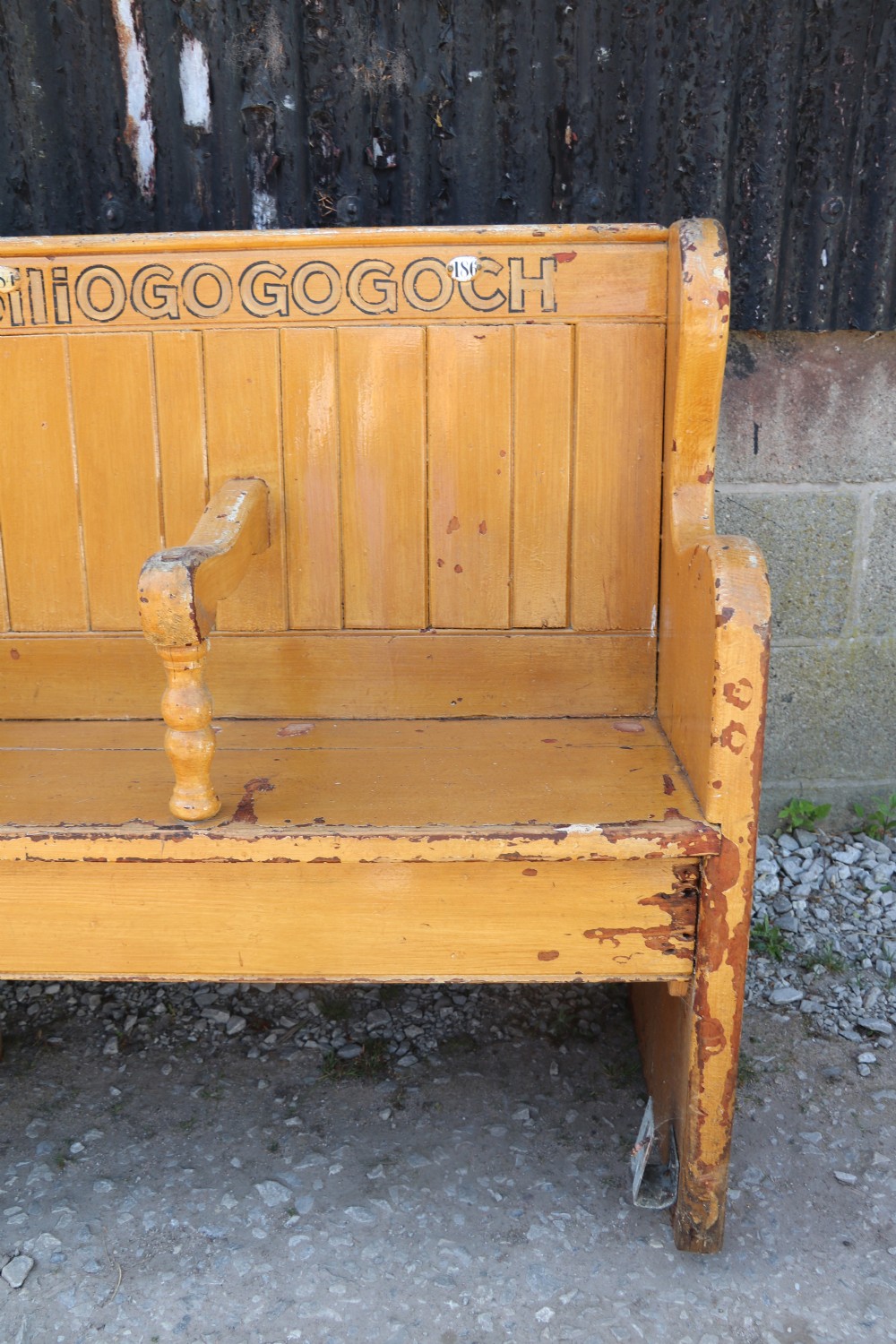 A long Victorian painted pine chapel bench featuring a vertical panelled back, turned arm dividers, and Welsh script along the top rail. View XIII