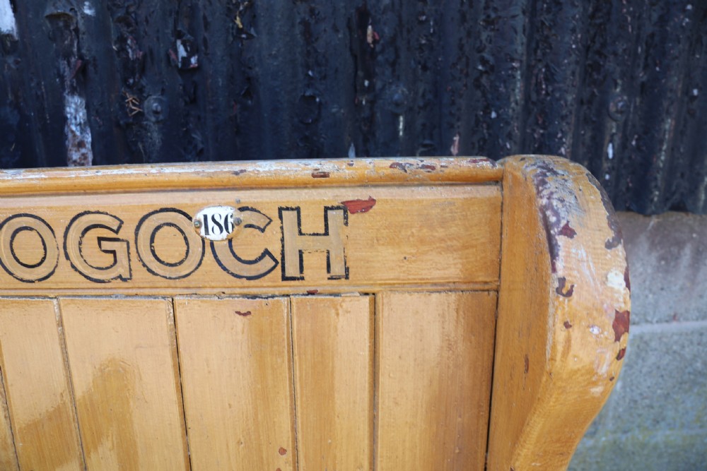 A long Victorian painted pine chapel bench featuring a vertical panelled back, turned arm dividers, and Welsh script along the top rail. View XXIII