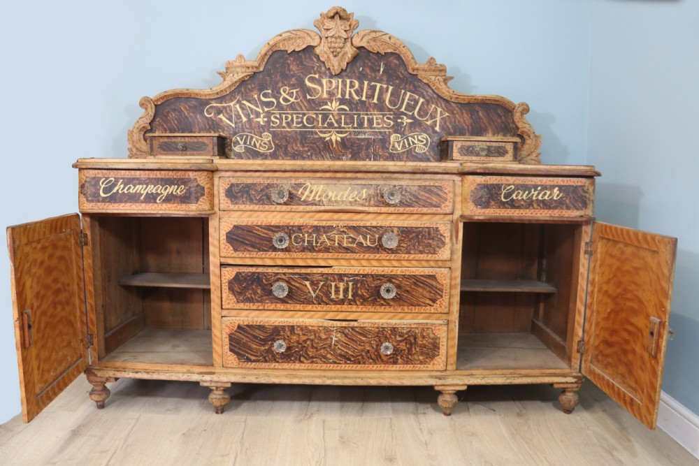 A nineteenth-century French Chateau style walnut sideboard featuring hand-painted French typography, decorative faux-marbling, a carved crest, and glass drawer knobs. View II