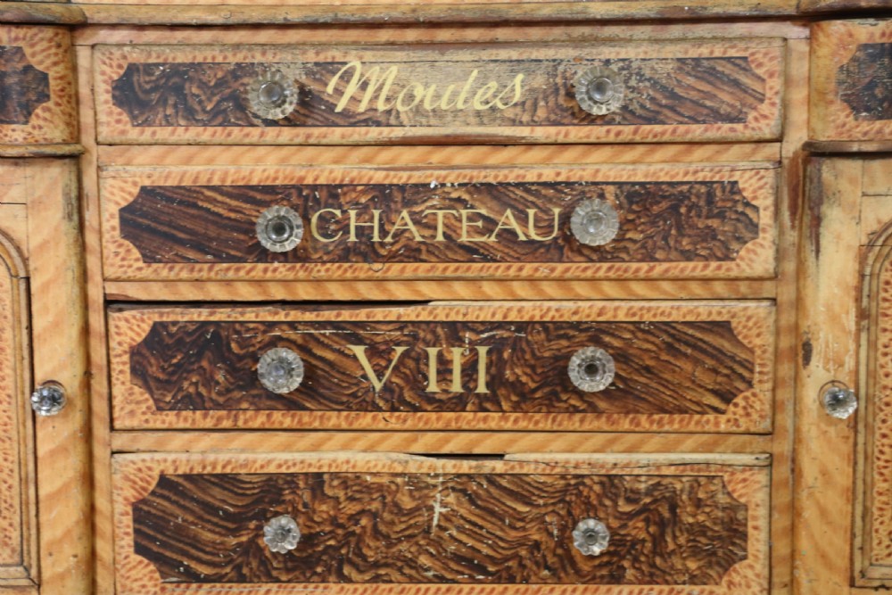 A nineteenth-century French Chateau style walnut sideboard featuring hand-painted French typography, decorative faux-marbling, a carved crest, and glass drawer knobs. View III