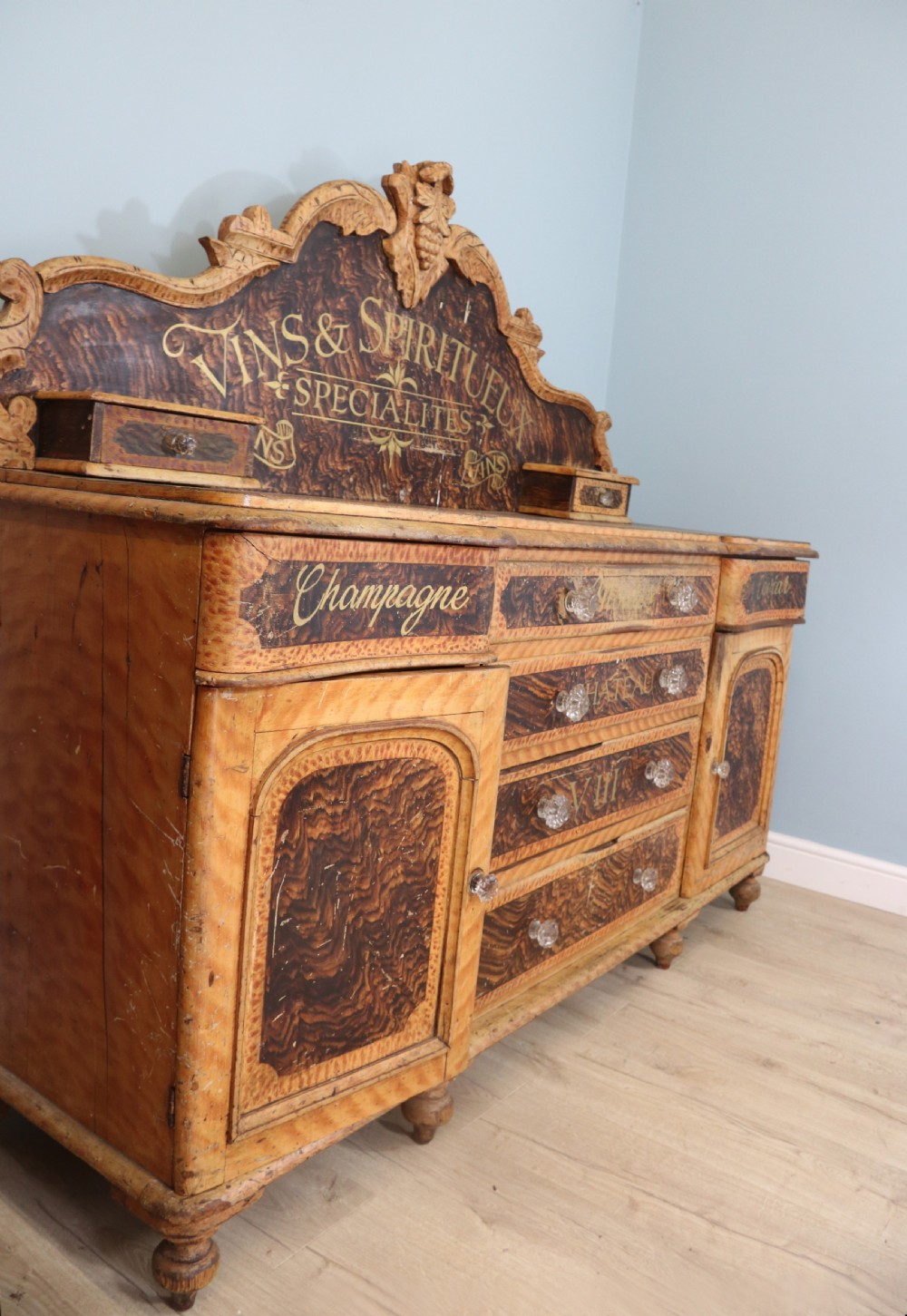 A nineteenth-century French Chateau style walnut sideboard featuring hand-painted French typography, decorative faux-marbling, a carved crest, and glass drawer knobs. View V