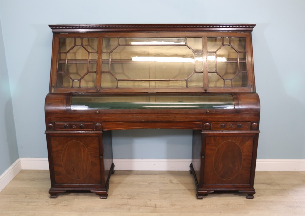 An early nineteenth-century mahogany twin pedestal display cabinet featuring glazed upper doors with geometric glazing bars, a central curved glass display section, and inlaid pedestal cupboards below.