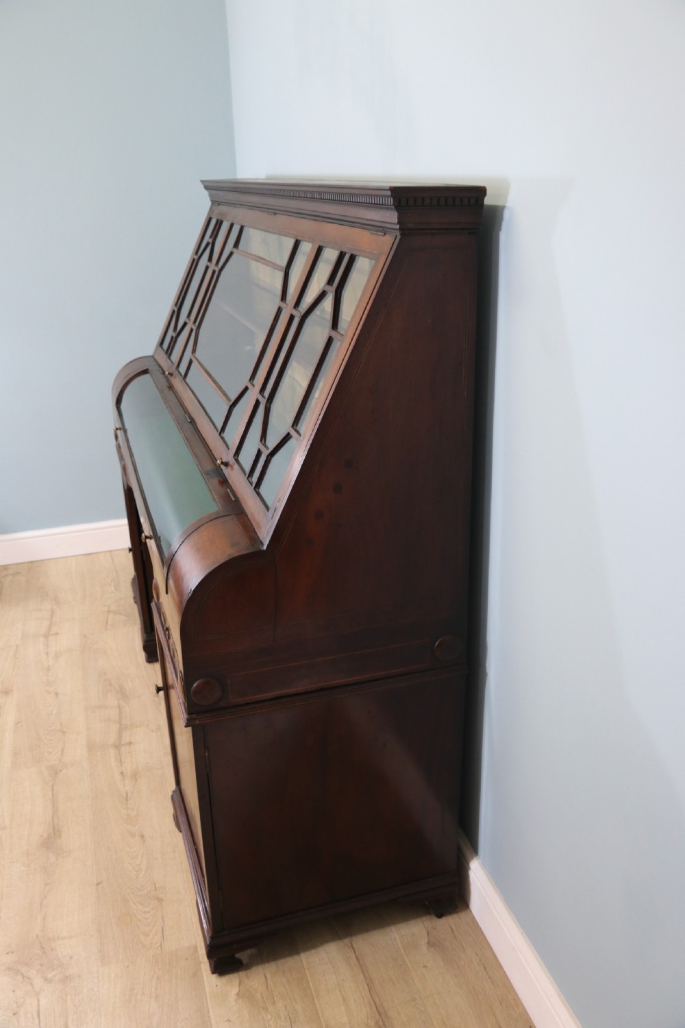 An early nineteenth-century mahogany twin pedestal display cabinet featuring glazed upper doors with geometric glazing bars, a central curved glass display section, and inlaid pedestal cupboards below. View VI