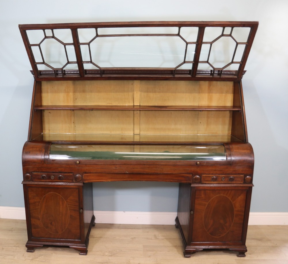 An early nineteenth-century mahogany twin pedestal display cabinet featuring glazed upper doors with geometric glazing bars, a central curved glass display section, and inlaid pedestal cupboards below. View XI