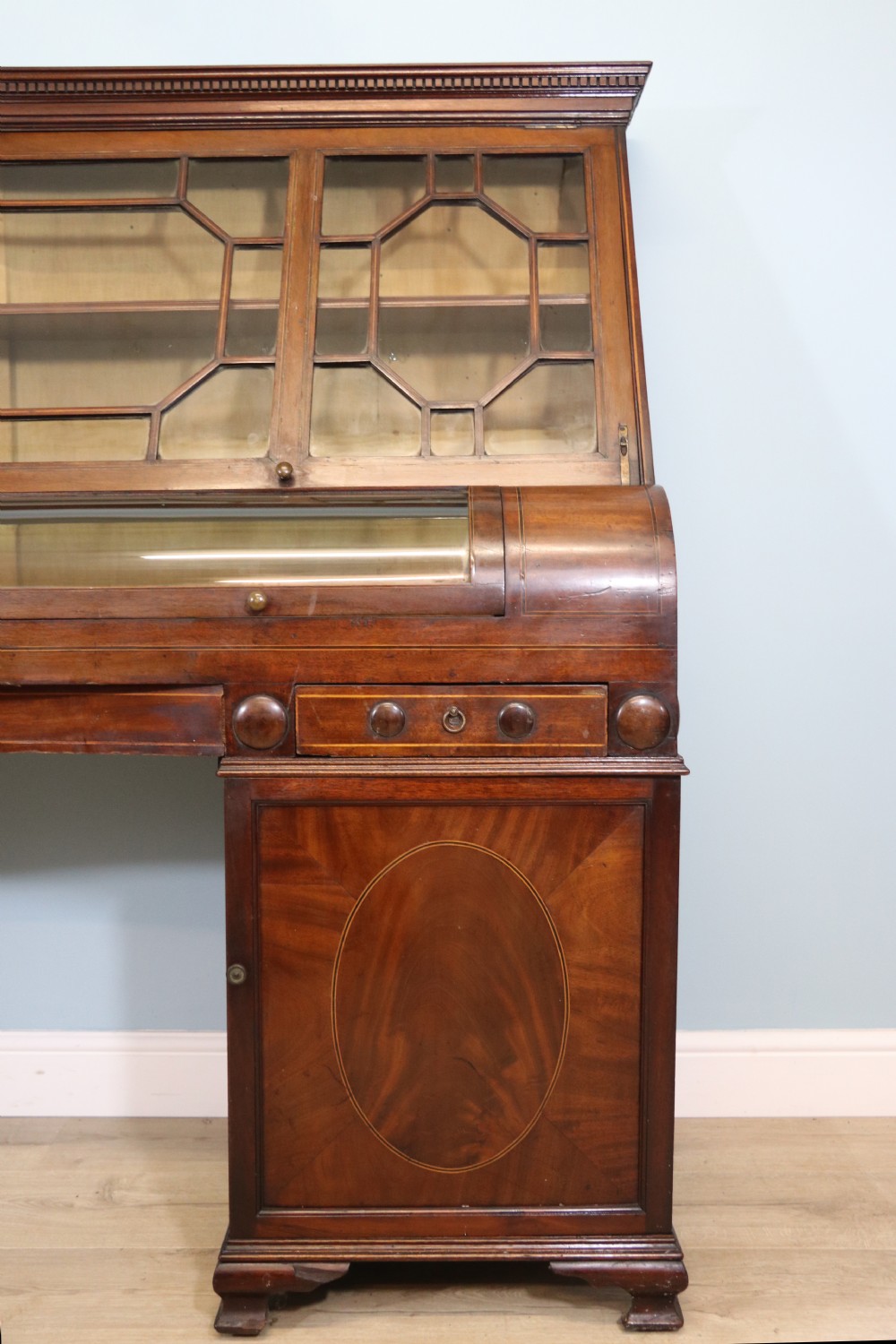 An early nineteenth-century mahogany twin pedestal display cabinet featuring glazed upper doors with geometric glazing bars, a central curved glass display section, and inlaid pedestal cupboards below. View XII