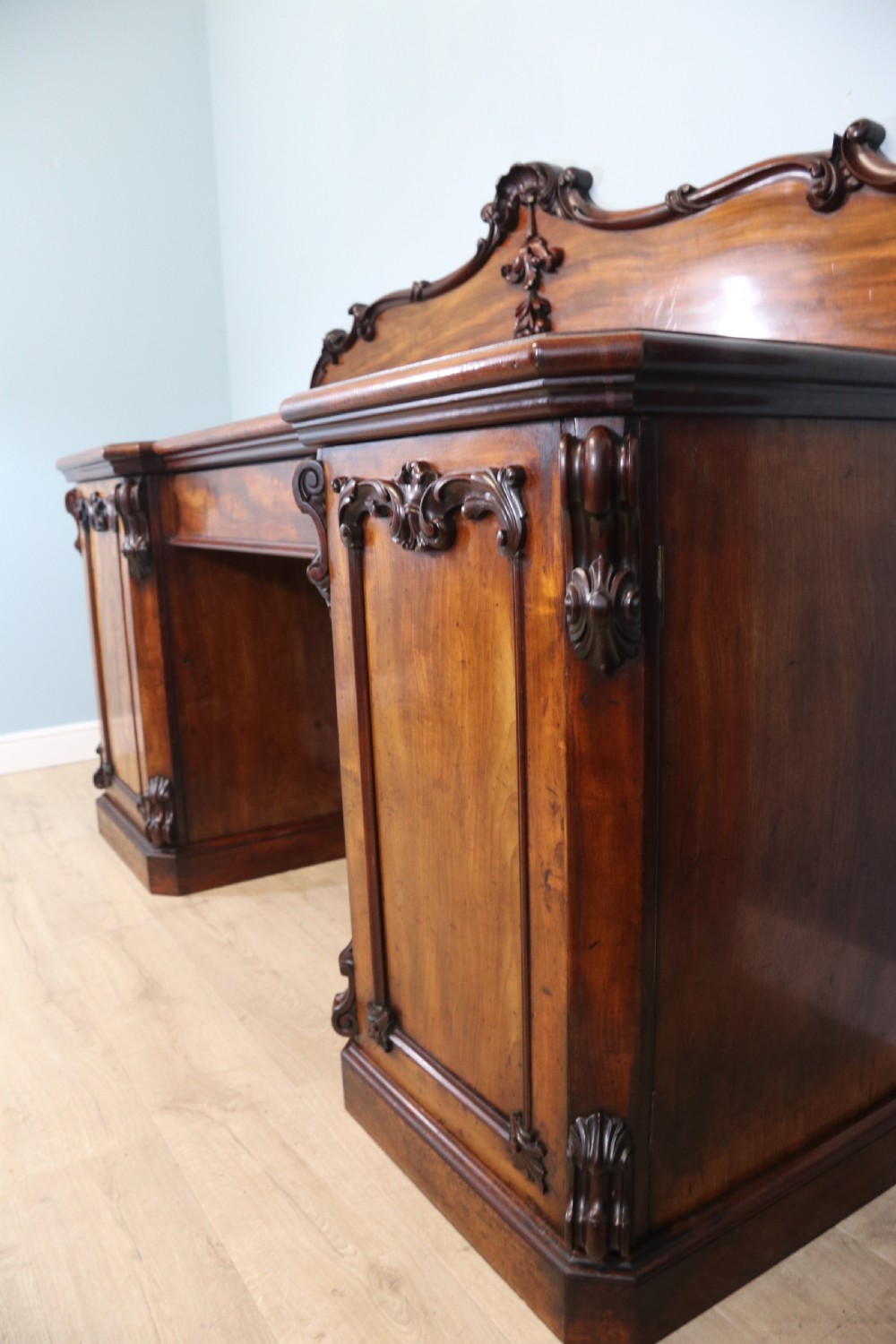 A Victorian mahogany twin pedestal sideboard featuring a central frieze drawer, carved splashback, and flame mahogany cupboard doors on plinth bases. View XVII