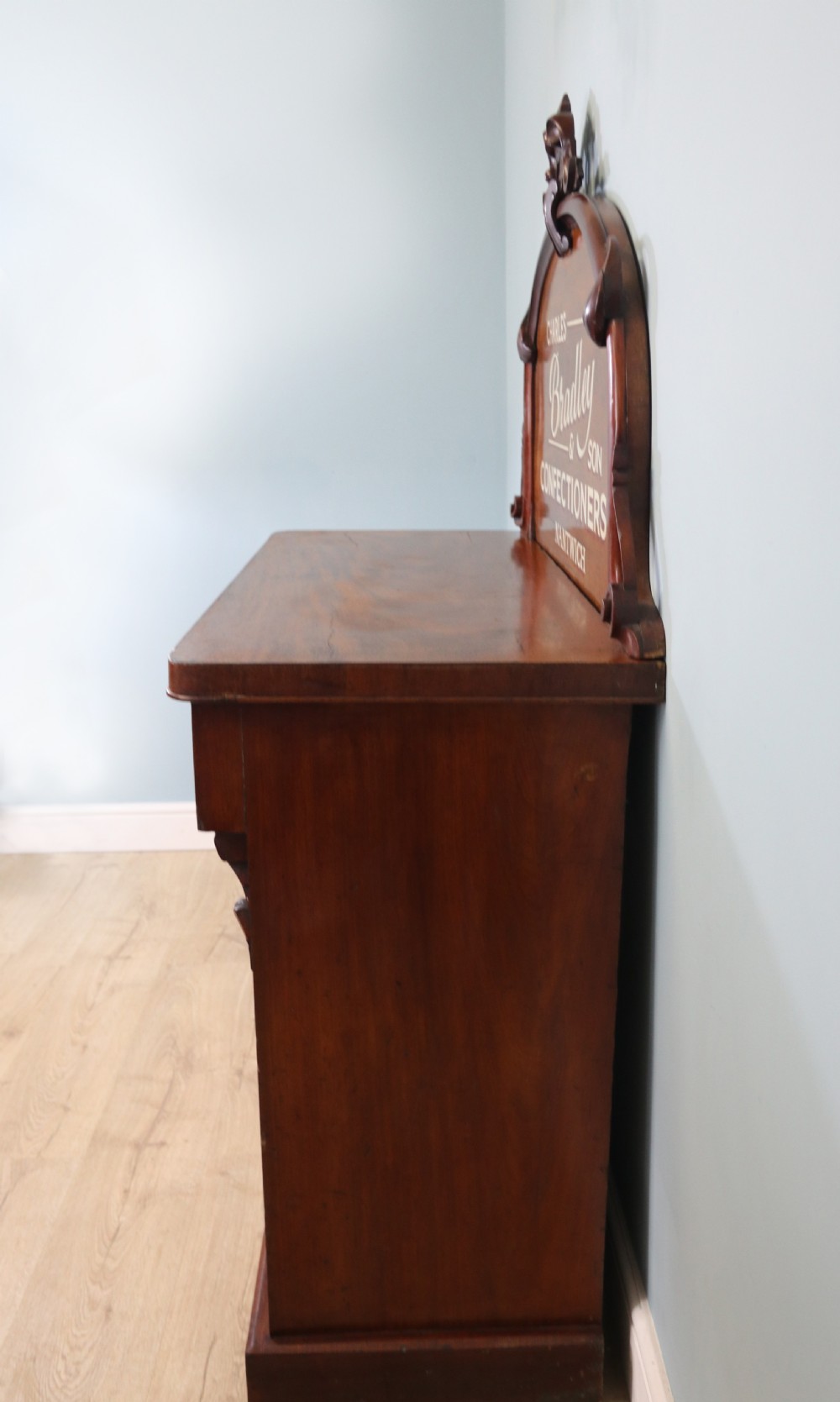 A Victorian mahogany chiffonier featuring hand-painted cream and red commercial typography across the upper cresting back and lower cupboard doors. View III