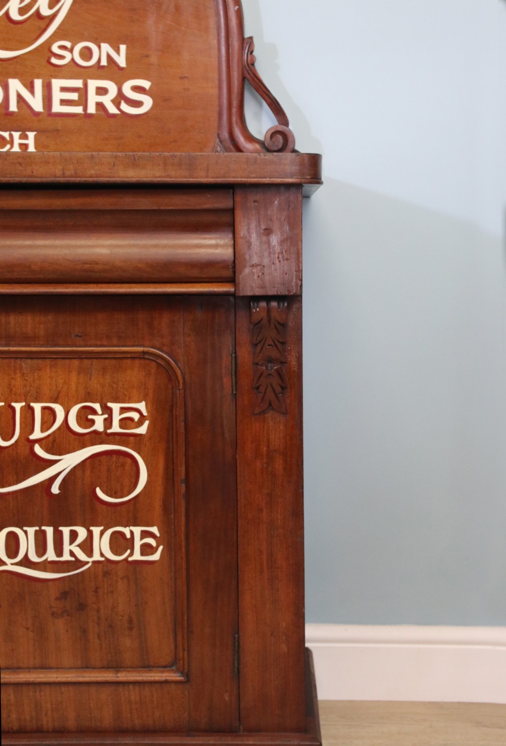 A Victorian mahogany chiffonier featuring hand-painted cream and red commercial typography across the upper cresting back and lower cupboard doors. View IV