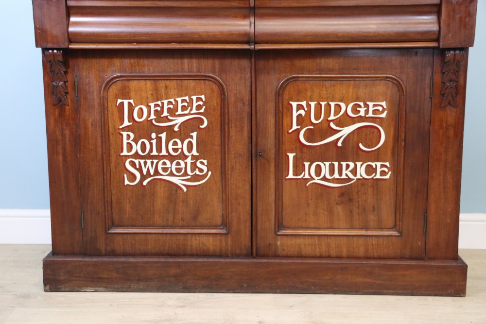 A Victorian mahogany chiffonier featuring hand-painted cream and red commercial typography across the upper cresting back and lower cupboard doors. View VI