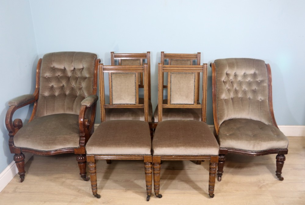 A six-piece late 19th-century chair suite featuring two button-back upholstered armchairs and four matching side chairs upholstered in taupe velvet with turned wooden front legs on castors.