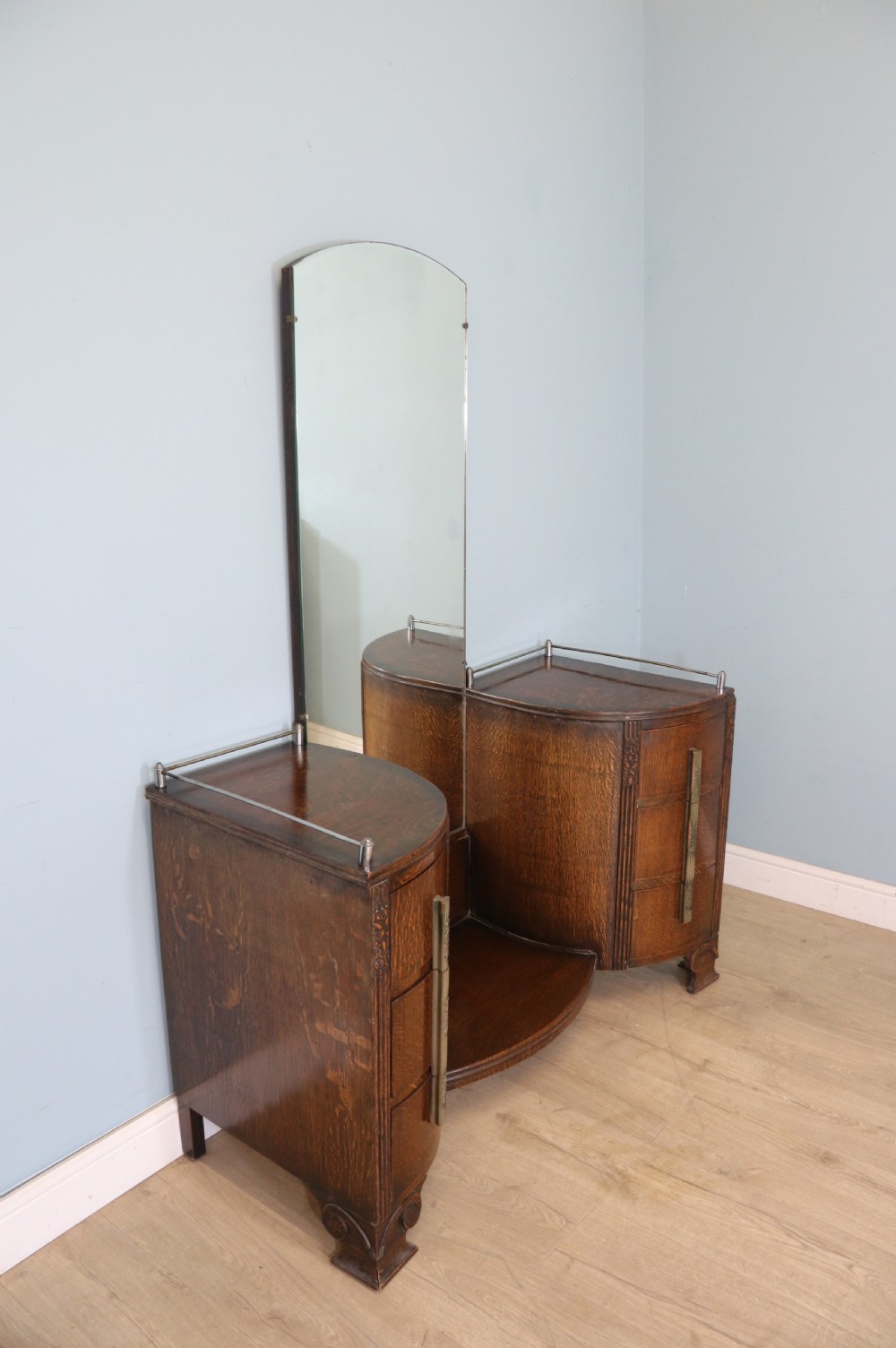 An Art Deco dark oak twin pedestal dressing chest featuring a central full-length arched mirror flanked by two curved three-drawer pedestals with metal gallery rails. View II