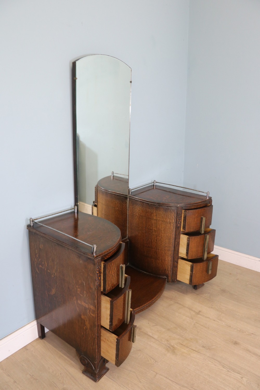 An Art Deco dark oak twin pedestal dressing chest featuring a central full-length arched mirror flanked by two curved three-drawer pedestals with metal gallery rails. View III