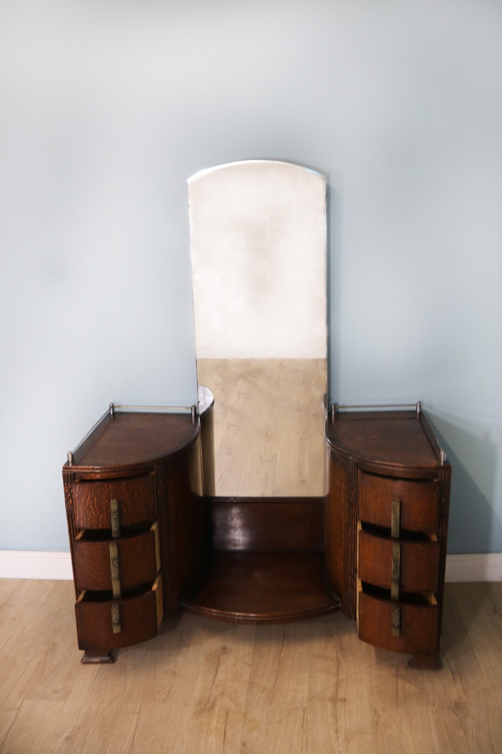 An Art Deco dark oak twin pedestal dressing chest featuring a central full-length arched mirror flanked by two curved three-drawer pedestals with metal gallery rails. View V