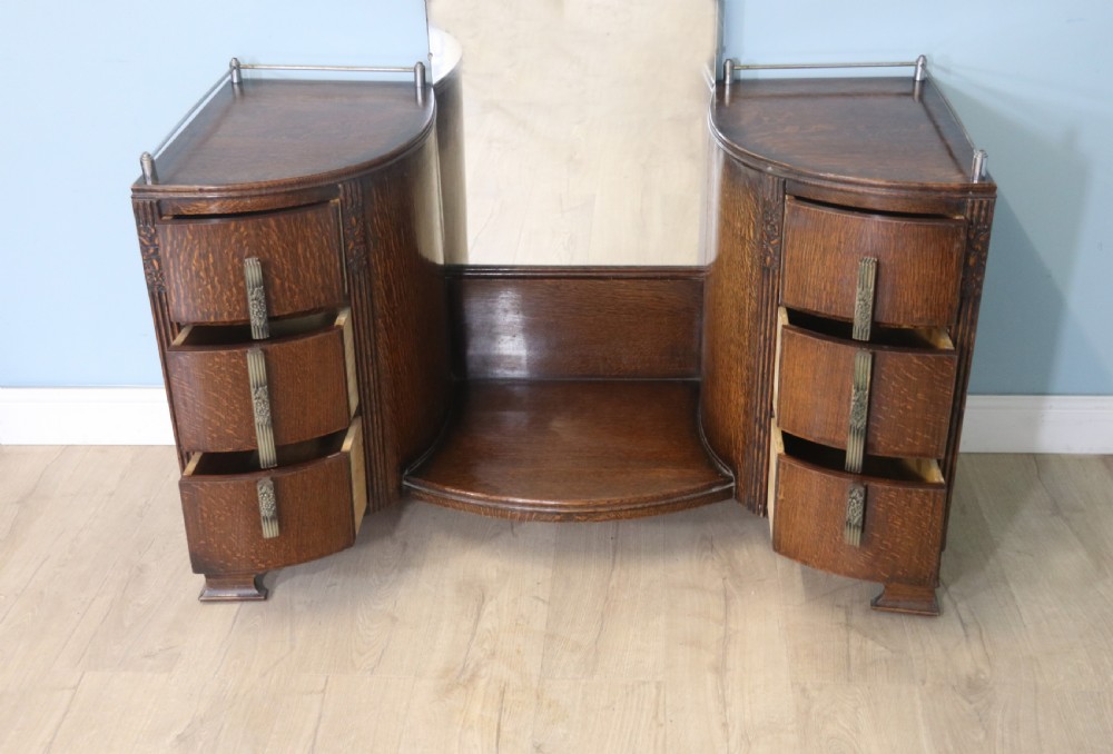 An Art Deco dark oak twin pedestal dressing chest featuring a central full-length arched mirror flanked by two curved three-drawer pedestals with metal gallery rails. View VI