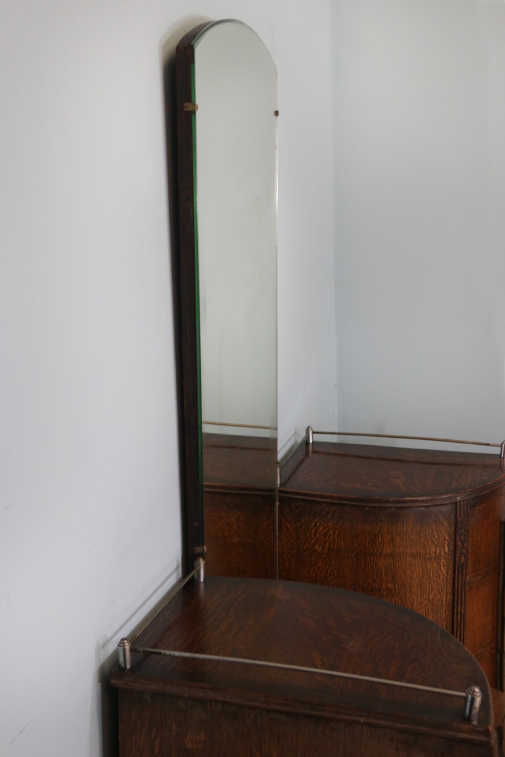 An Art Deco dark oak twin pedestal dressing chest featuring a central full-length arched mirror flanked by two curved three-drawer pedestals with metal gallery rails. View X