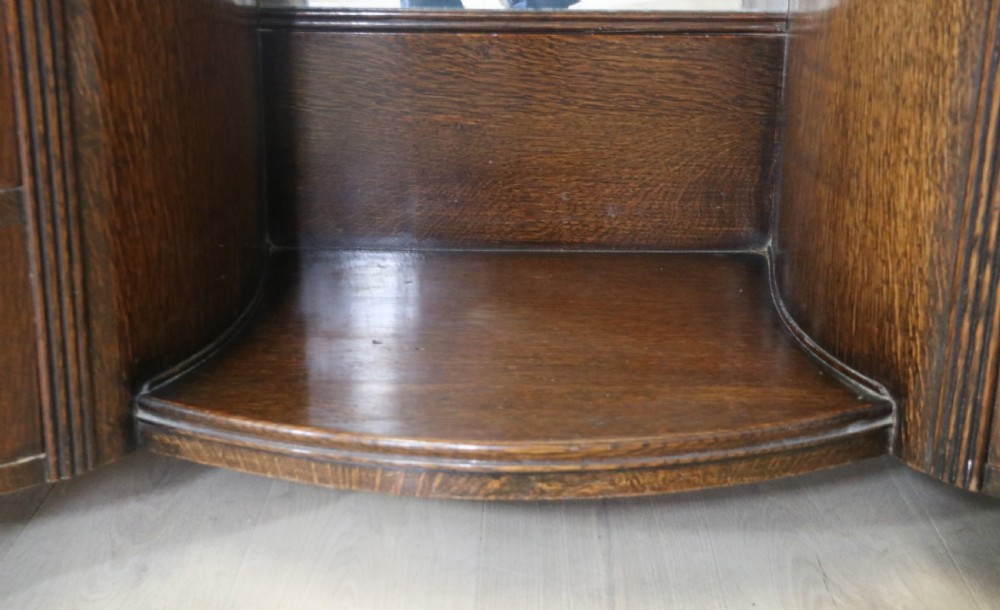 An Art Deco dark oak twin pedestal dressing chest featuring a central full-length arched mirror flanked by two curved three-drawer pedestals with metal gallery rails. View XII
