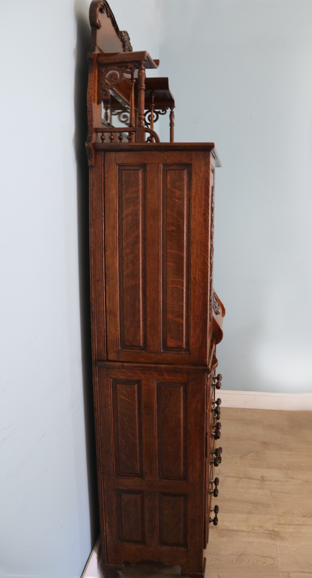A late nineteenth-century oak combination dentist cabinet featuring a mirrored gallery top, carved foliate door, tambour section, and multiple small drawers. View IX