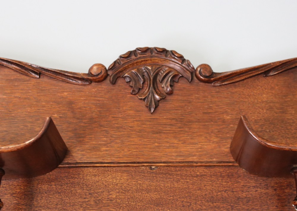 A late nineteenth-century oak combination dentist cabinet featuring a mirrored gallery top, carved foliate door, tambour section, and multiple small drawers. View XI