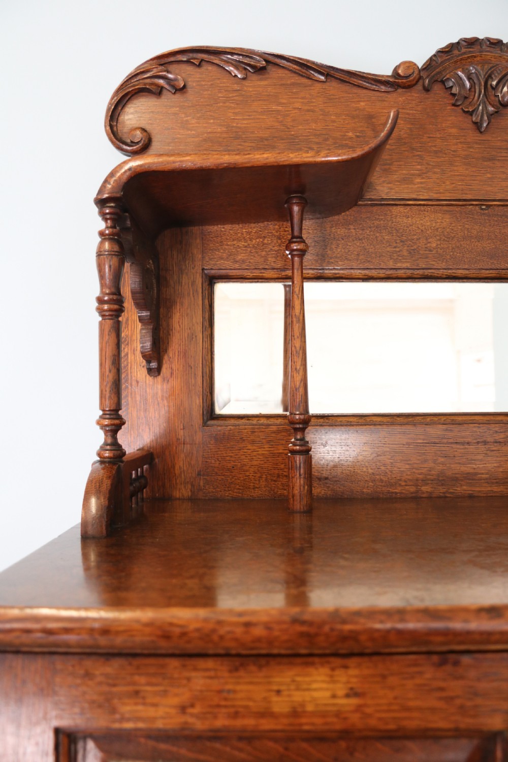 A late nineteenth-century oak combination dentist cabinet featuring a mirrored gallery top, carved foliate door, tambour section, and multiple small drawers. View XII