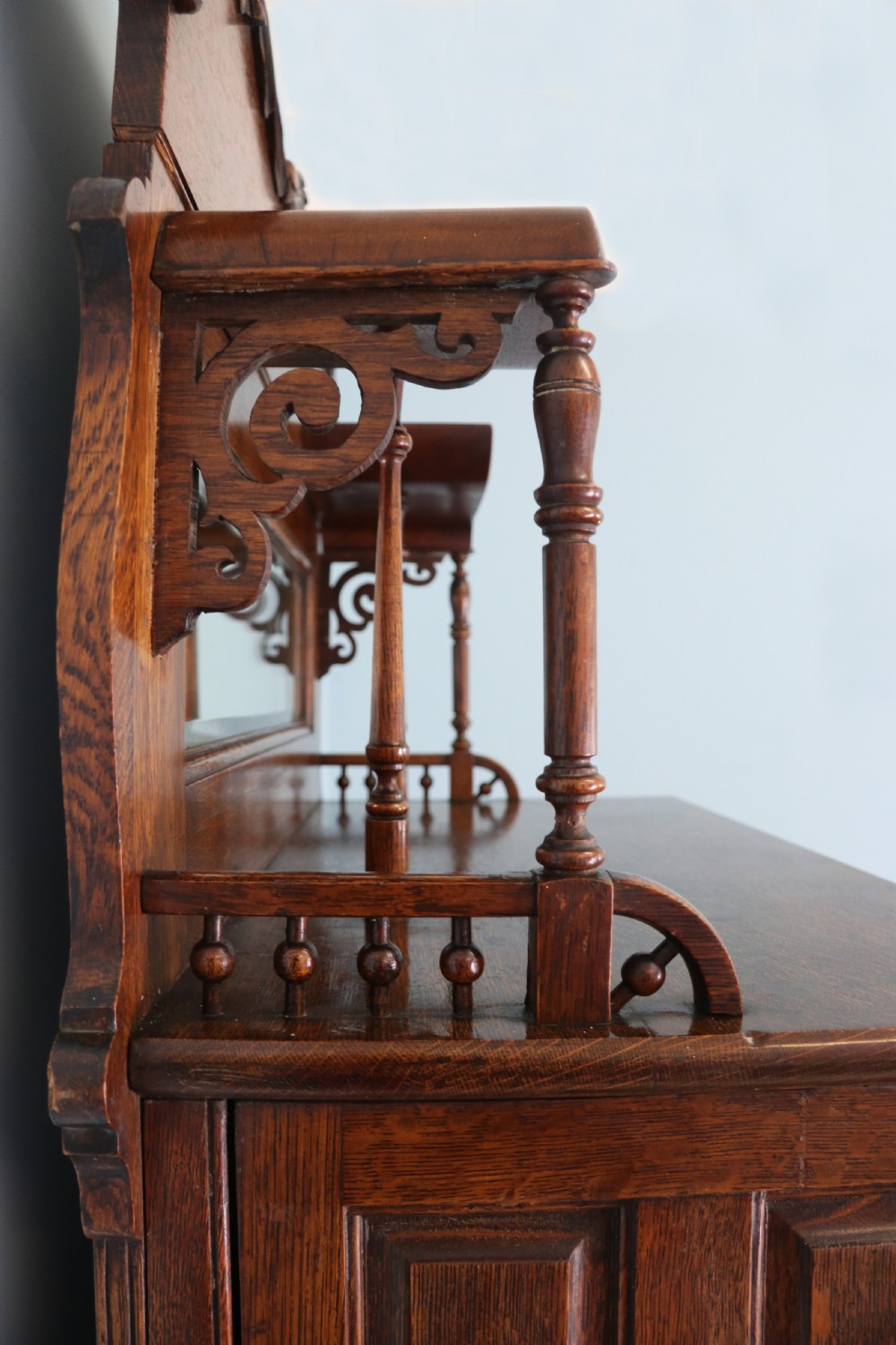 A late nineteenth-century oak combination dentist cabinet featuring a mirrored gallery top, carved foliate door, tambour section, and multiple small drawers. View XIII