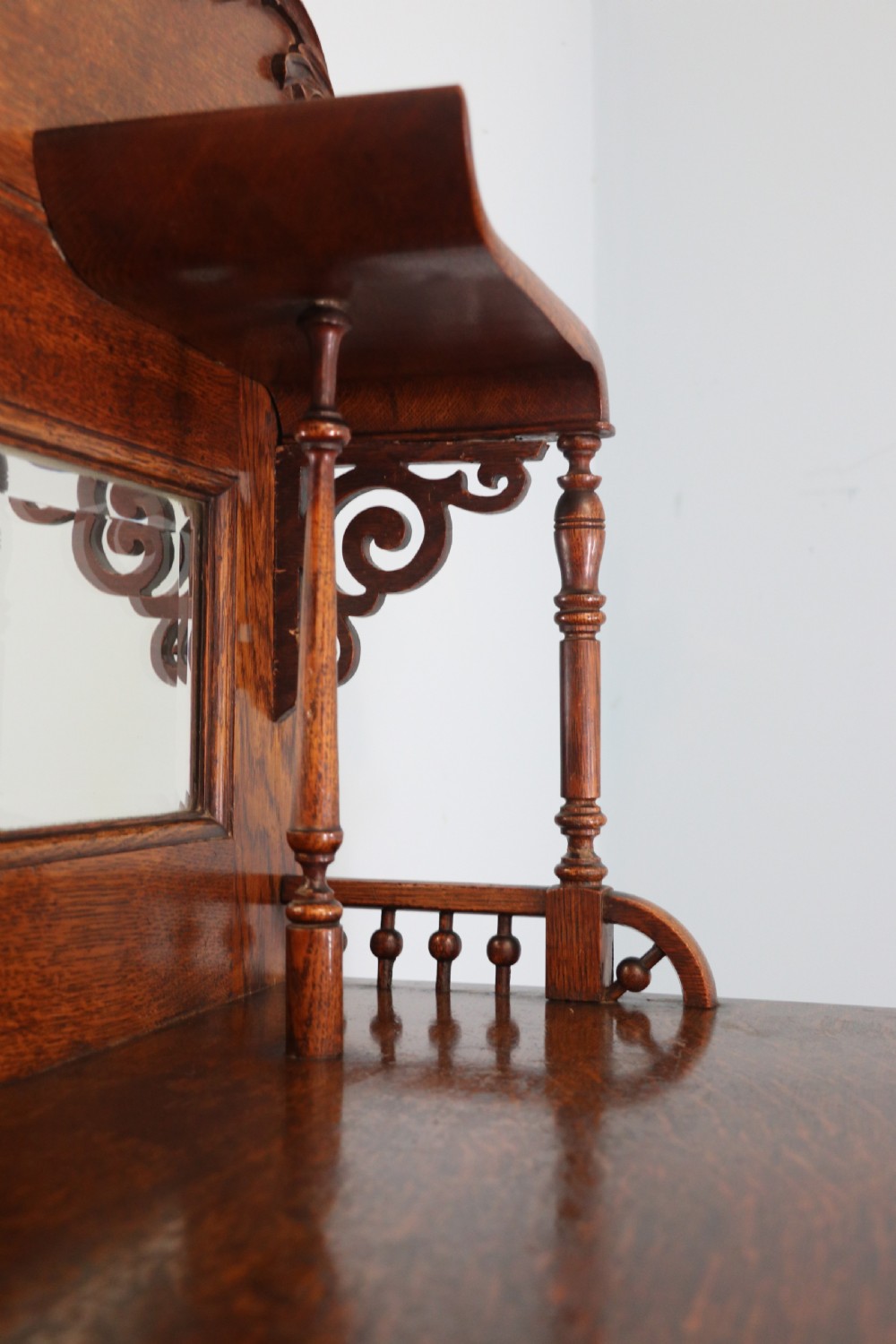 A late nineteenth-century oak combination dentist cabinet featuring a mirrored gallery top, carved foliate door, tambour section, and multiple small drawers. View XIV