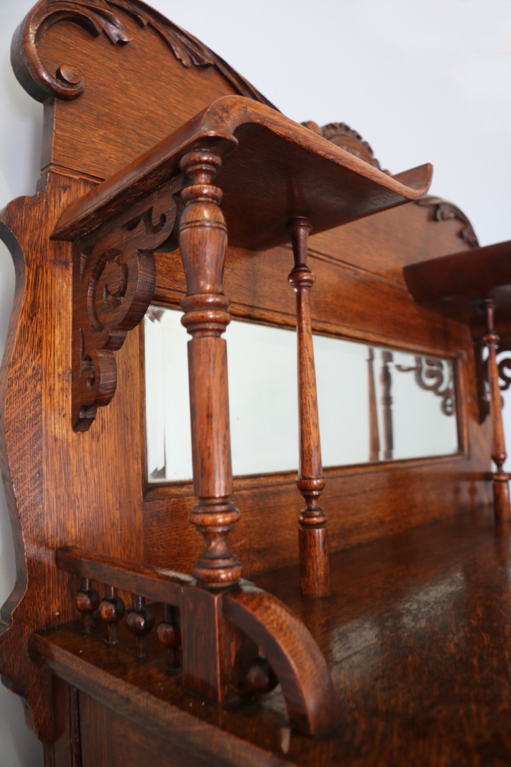 A late nineteenth-century oak combination dentist cabinet featuring a mirrored gallery top, carved foliate door, tambour section, and multiple small drawers. View XV