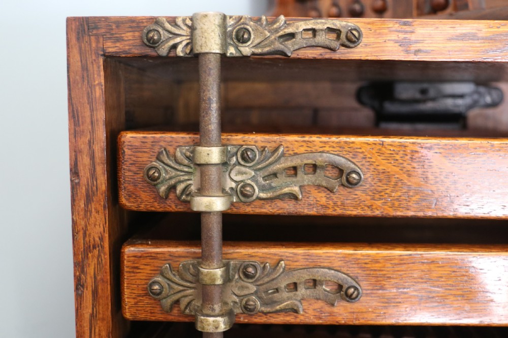 A late nineteenth-century oak combination dentist cabinet featuring a mirrored gallery top, carved foliate door, tambour section, and multiple small drawers. View XX
