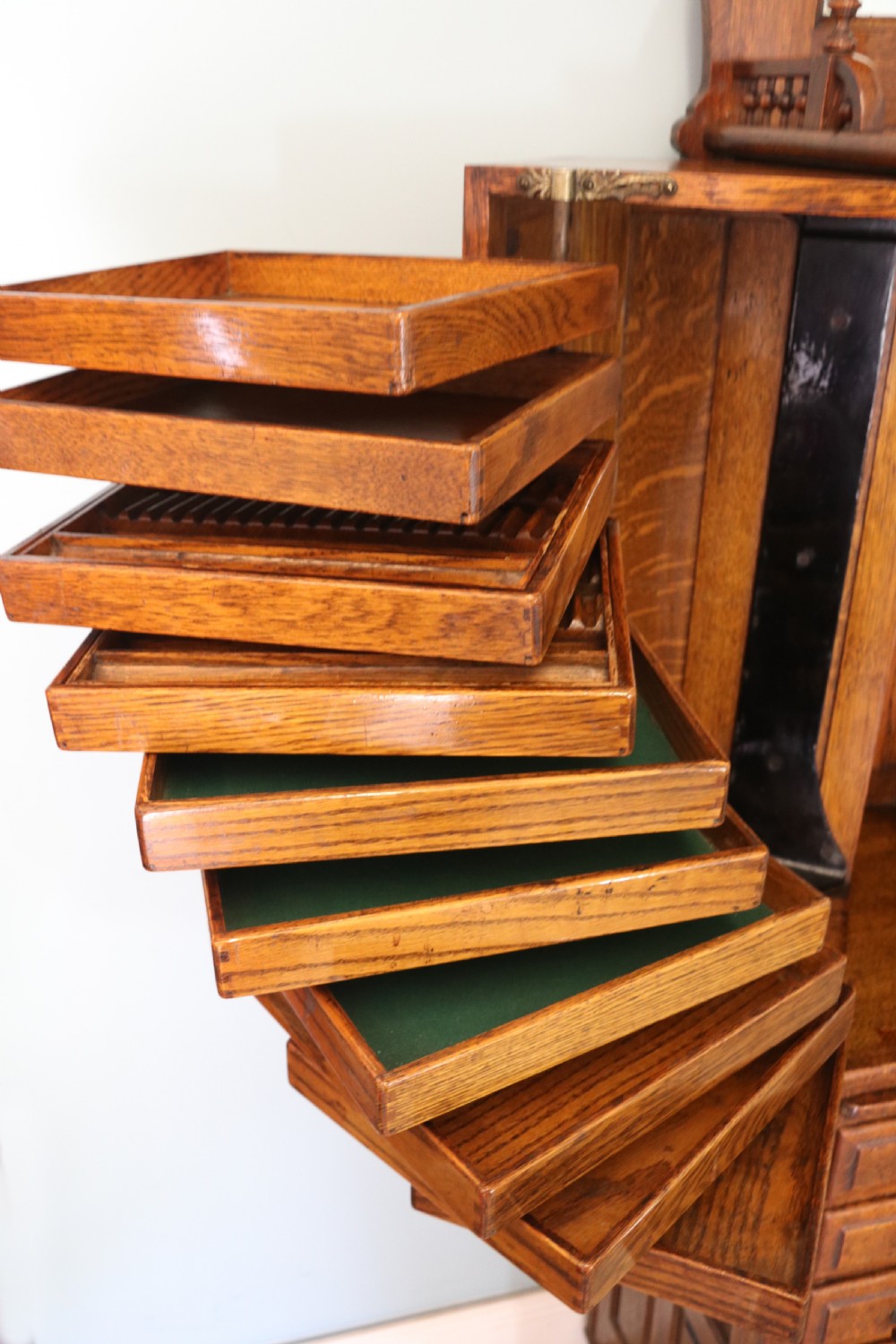 A late nineteenth-century oak combination dentist cabinet featuring a mirrored gallery top, carved foliate door, tambour section, and multiple small drawers. View XXI