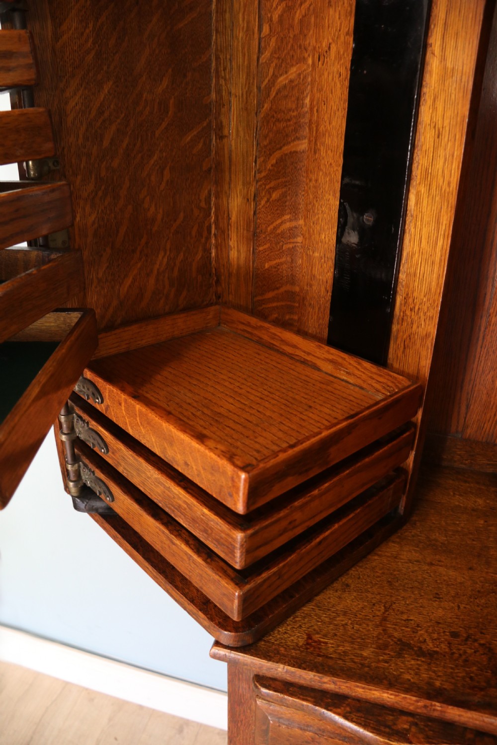 A late nineteenth-century oak combination dentist cabinet featuring a mirrored gallery top, carved foliate door, tambour section, and multiple small drawers. View XXVI