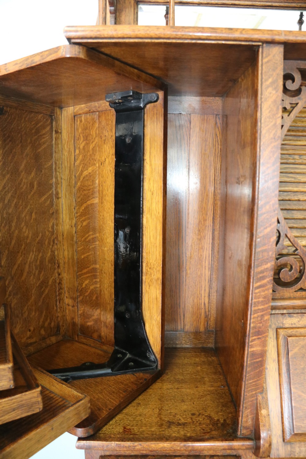 A late nineteenth-century oak combination dentist cabinet featuring a mirrored gallery top, carved foliate door, tambour section, and multiple small drawers. View XXVII