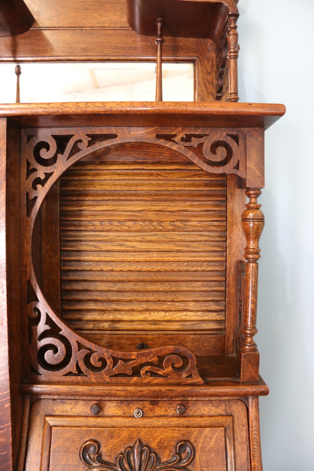 A late nineteenth-century oak combination dentist cabinet featuring a mirrored gallery top, carved foliate door, tambour section, and multiple small drawers. View XXIX