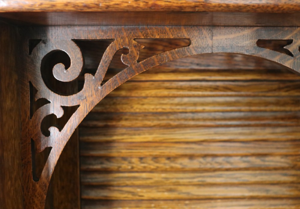 A late nineteenth-century oak combination dentist cabinet featuring a mirrored gallery top, carved foliate door, tambour section, and multiple small drawers. View XXX