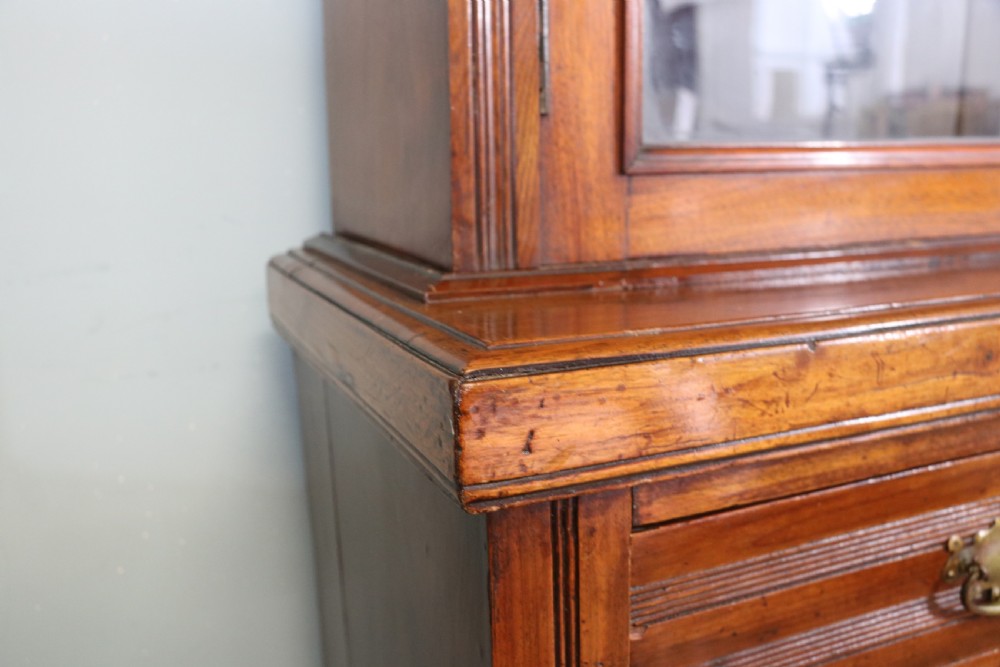 A two-tier dark walnut display cabinet featuring glazed upper doors decorated with vintage Cadburys advertising lettering above lower carved wooden cupboard doors. View XIV