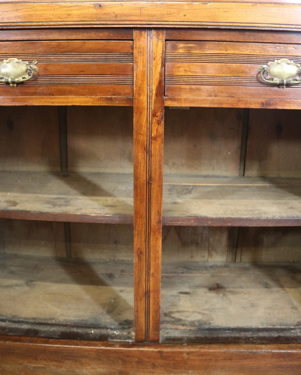 A two-tier dark walnut display cabinet featuring glazed upper doors decorated with vintage Cadburys advertising lettering above lower carved wooden cupboard doors. View XVI