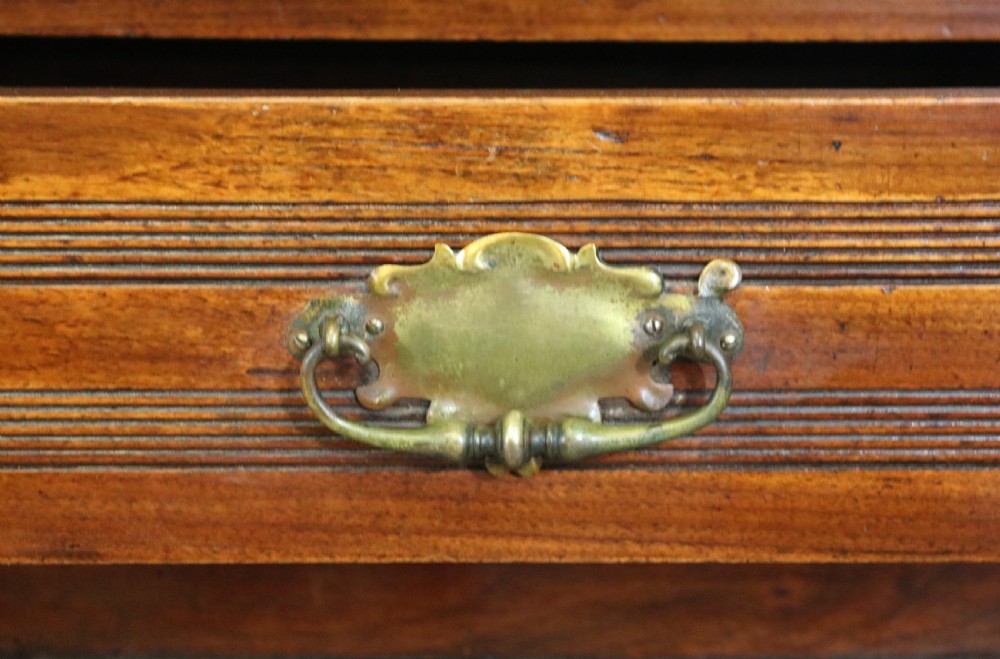 A two-tier dark walnut display cabinet featuring glazed upper doors decorated with vintage Cadburys advertising lettering above lower carved wooden cupboard doors. View XVII