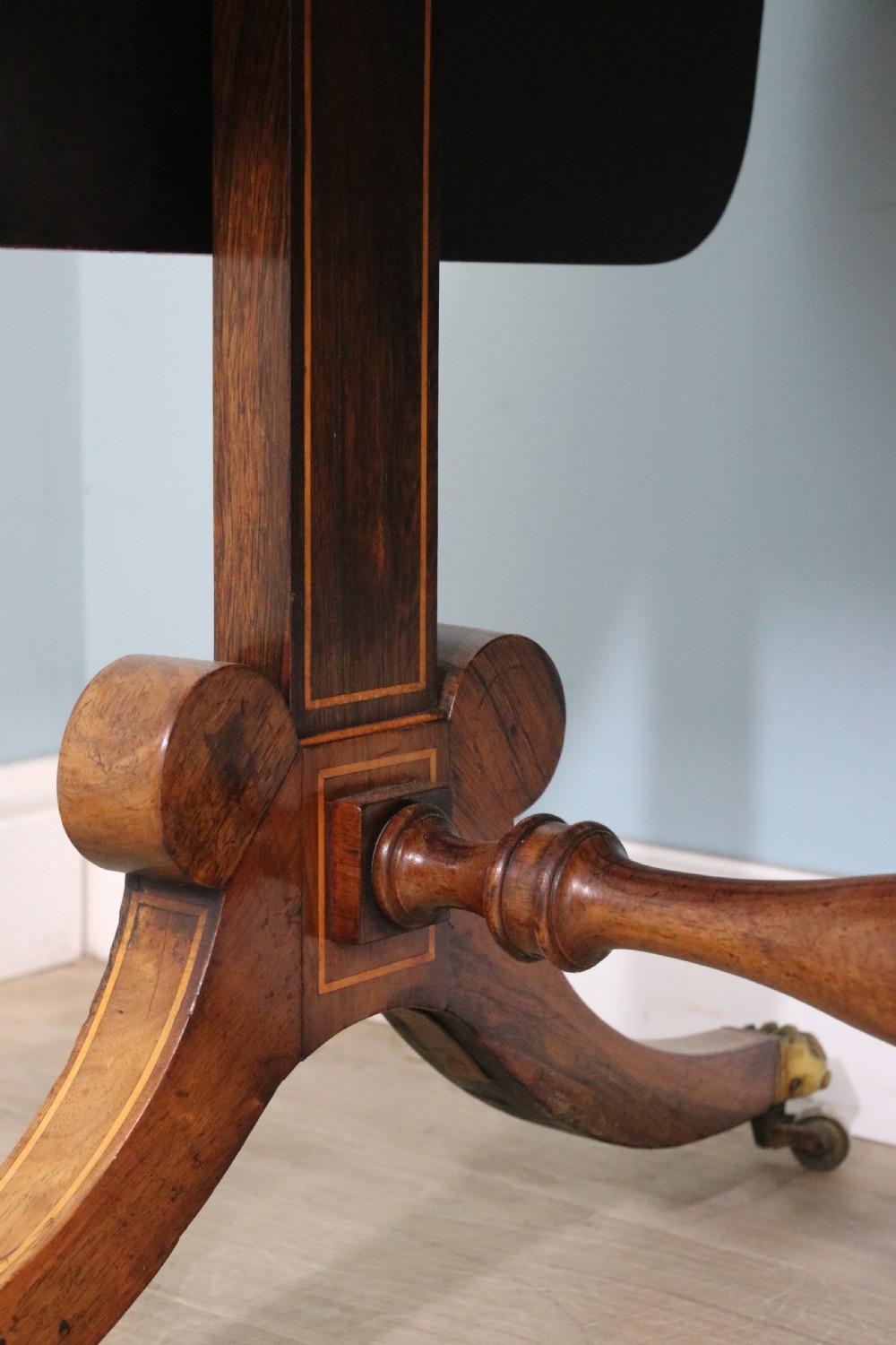 An early 19th-century Regency drop-leaf sofa table made of polished dark wood with two drawers, brass mounts, turned stretcher, and splayed legs with brass paw castors. View XXII