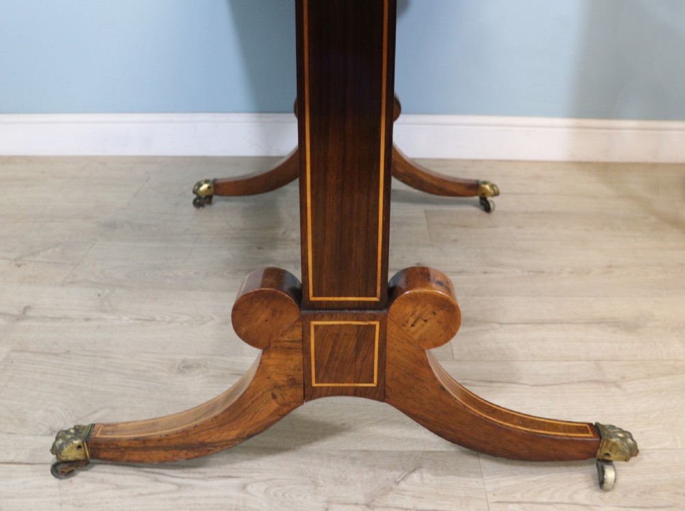 An early 19th-century Regency drop-leaf sofa table made of polished dark wood with two drawers, brass mounts, turned stretcher, and splayed legs with brass paw castors. View XXIII