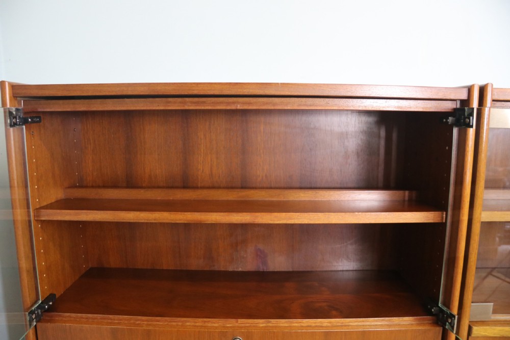 A pair of mid-century teak display cabinets featuring upper sliding glass doors, internal shelving, lower wooden cupboards, drawers, and brass fittings. View IV
